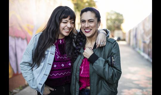 latino women smiling and laughing in mural alley