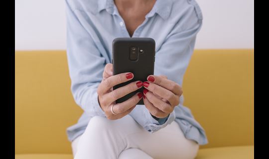 woman using smartphone on yellow couch
