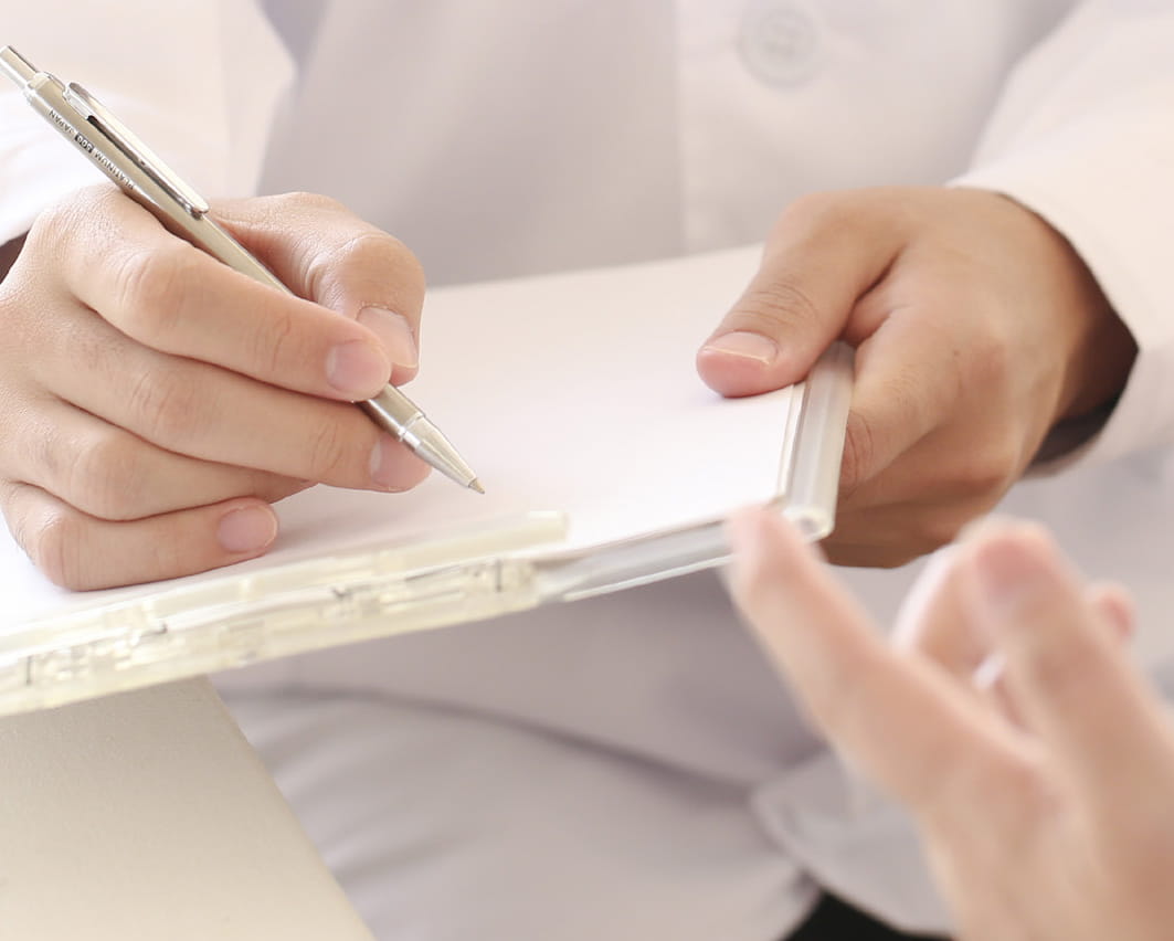 Close up of doctor's hand writing on a patient chart